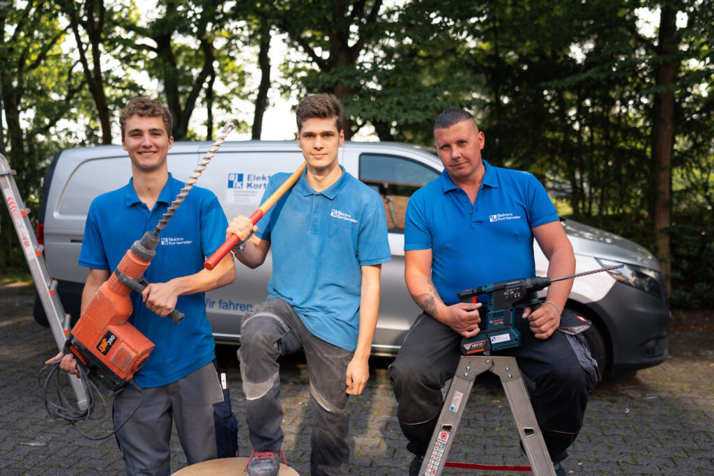 3 Junge Elektriker mit Werkzeug in der Hand vor Firmenbulli